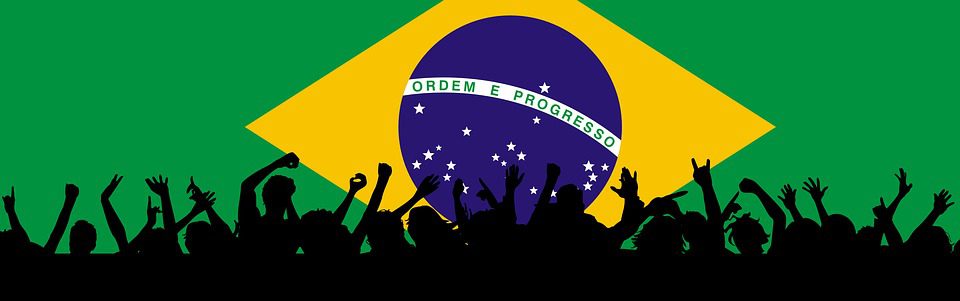 Pessoas comemoram, ao fundo bandeira do Brasil